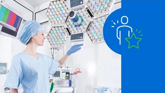 Medical professional in an operating room pointing at a monitor, with surgical lights in the background and a person-star icon on a blue panel.