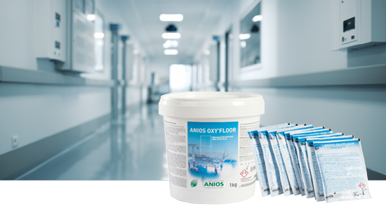 Container and packets of ANIOS OXY'FLOOR disinfectant in a clean hospital corridor, labeled with product name and weight.
